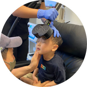 A child receiving MeRT treatment seated with the device on their head